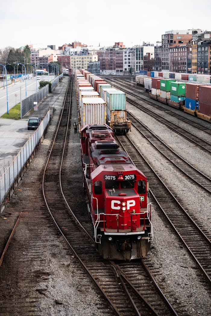 A red freight train with containers at a rail yard in Vancouver, showcasing industrial transportation.