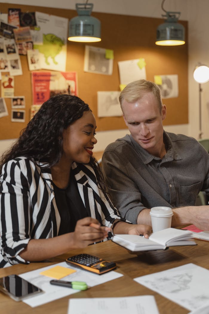 Two diverse professionals engaged in a collaborative discussion in a creative office space.