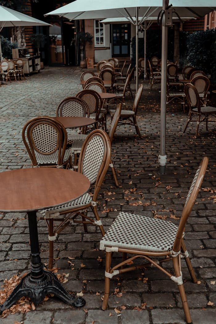 Cozy outdoor café in Paris with vintage chairs, tables, and umbrellas on stone pavement.